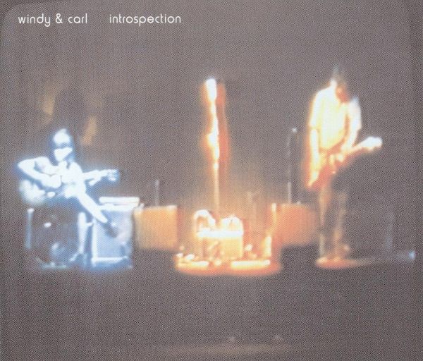 It's a night photo of Windy and Carl on a stage performing. Their figures are a bit distorted and ghost-like due to the lighting conditions and the blurriness of the photo and the printing