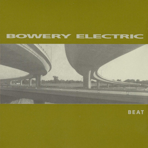 Olive green cover with a landscape photography in the middle, side-to-side, of road junctions, viewed from below. Above the photo is the album's title